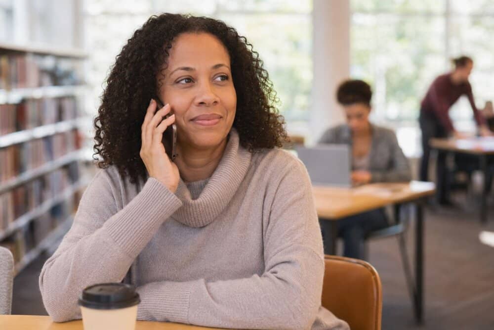 A person calling a support line from a safe public place before removing spyware