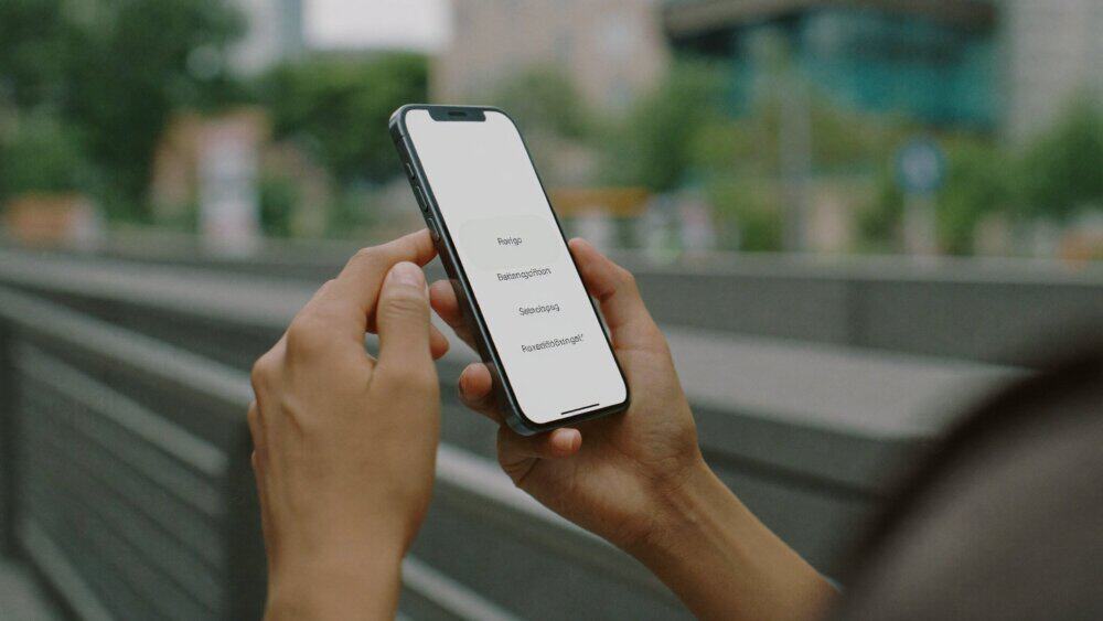 A person standing outdoors in a city using a smartphone securely on the go