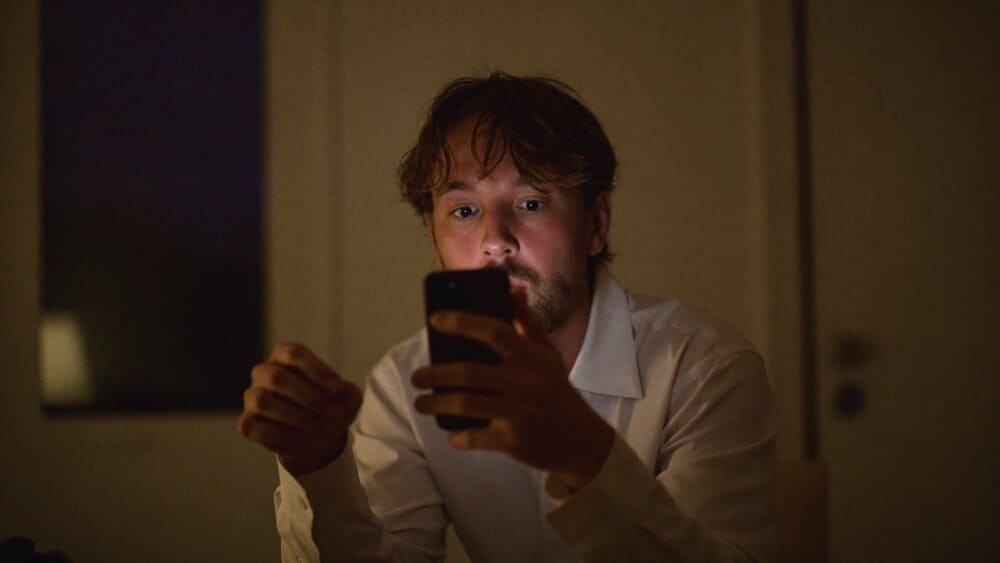 Person looking uneasily at their iPhone at night