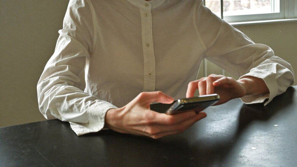 A parent setting up parental controls on a smartphone at a kitchen table