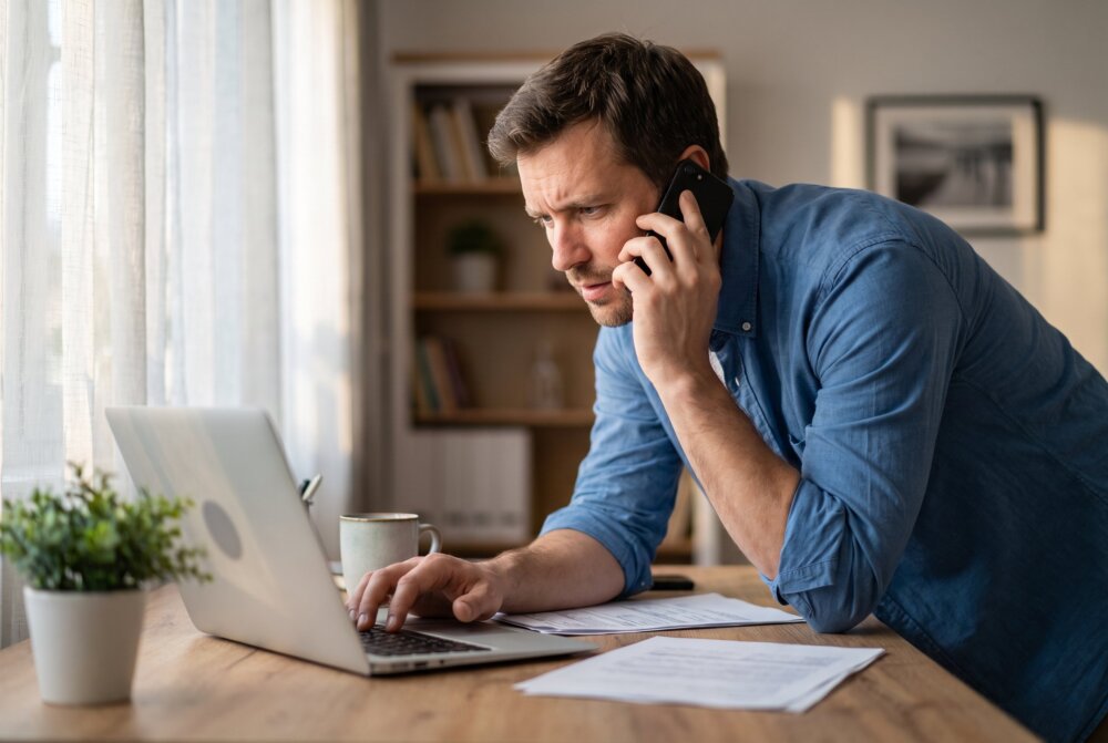 Man troubleshooting his phone at a home office desk